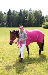 ピンクのラグを着た馬を曳く若い女の子